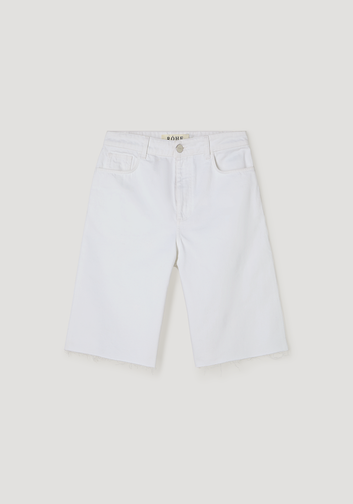 Baggy fit denim shorts in optic white, featuring knee-length Bermuda style, raw frayed hem, classic five-pocket design, and a relaxed, casual look.