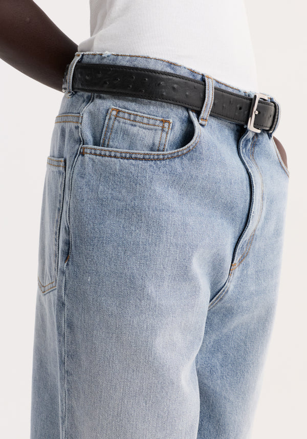 Close-up of Baggy fit denim shorts in classic blue with contrast stitching, raw hemline, and black leather belt; white ribbed tank tucked in.