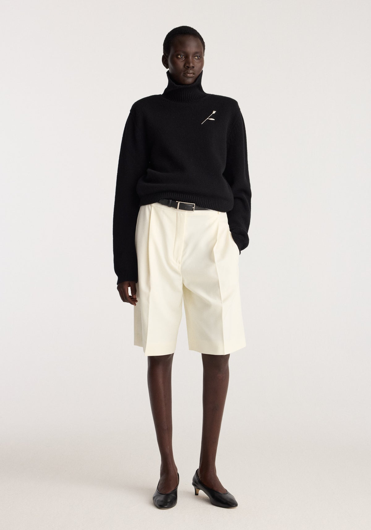 Tulip silver brooch | silver pinned to the chest of a black turtleneck, styled with cream tailored shorts and black shoes on a fashion model