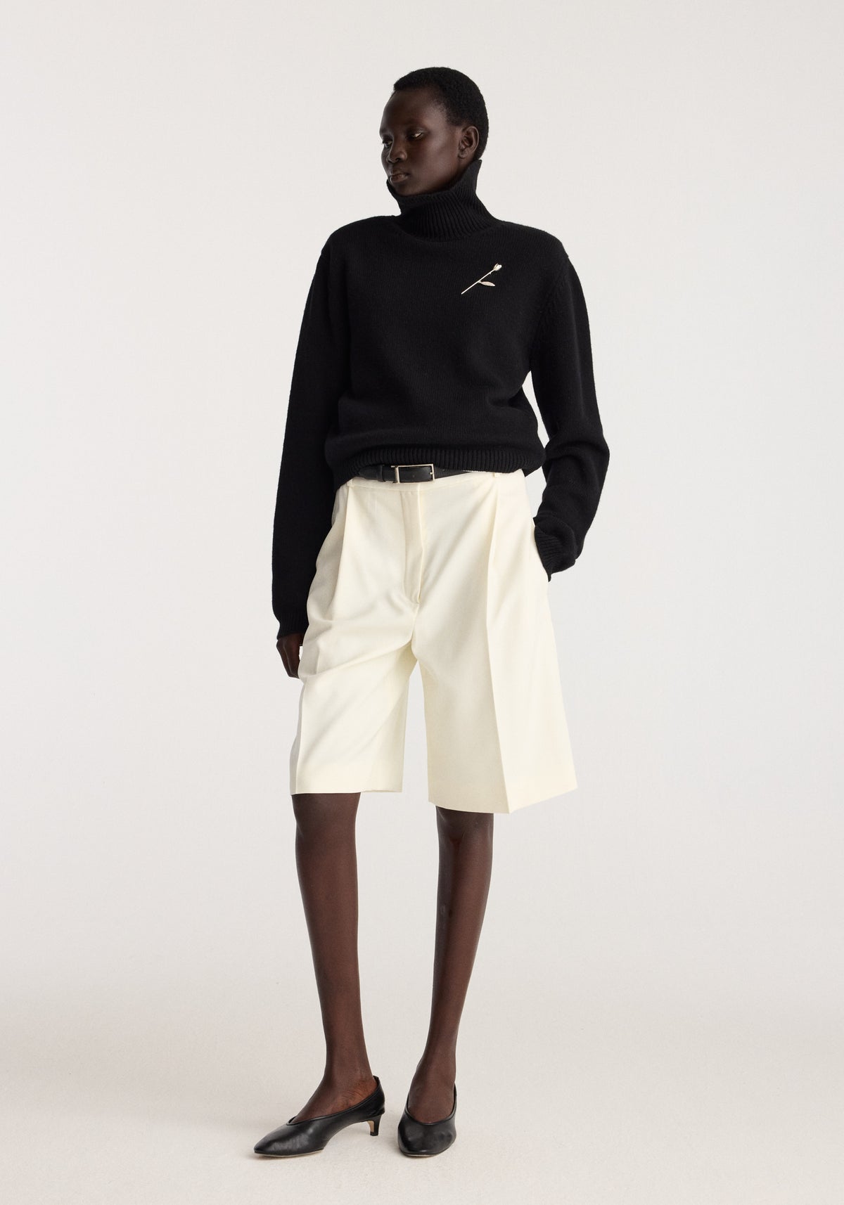 Tulip silver brooch | silver pinned to a black sweater, featuring a delicate silver tulip design worn by a model in a minimalist studio setting