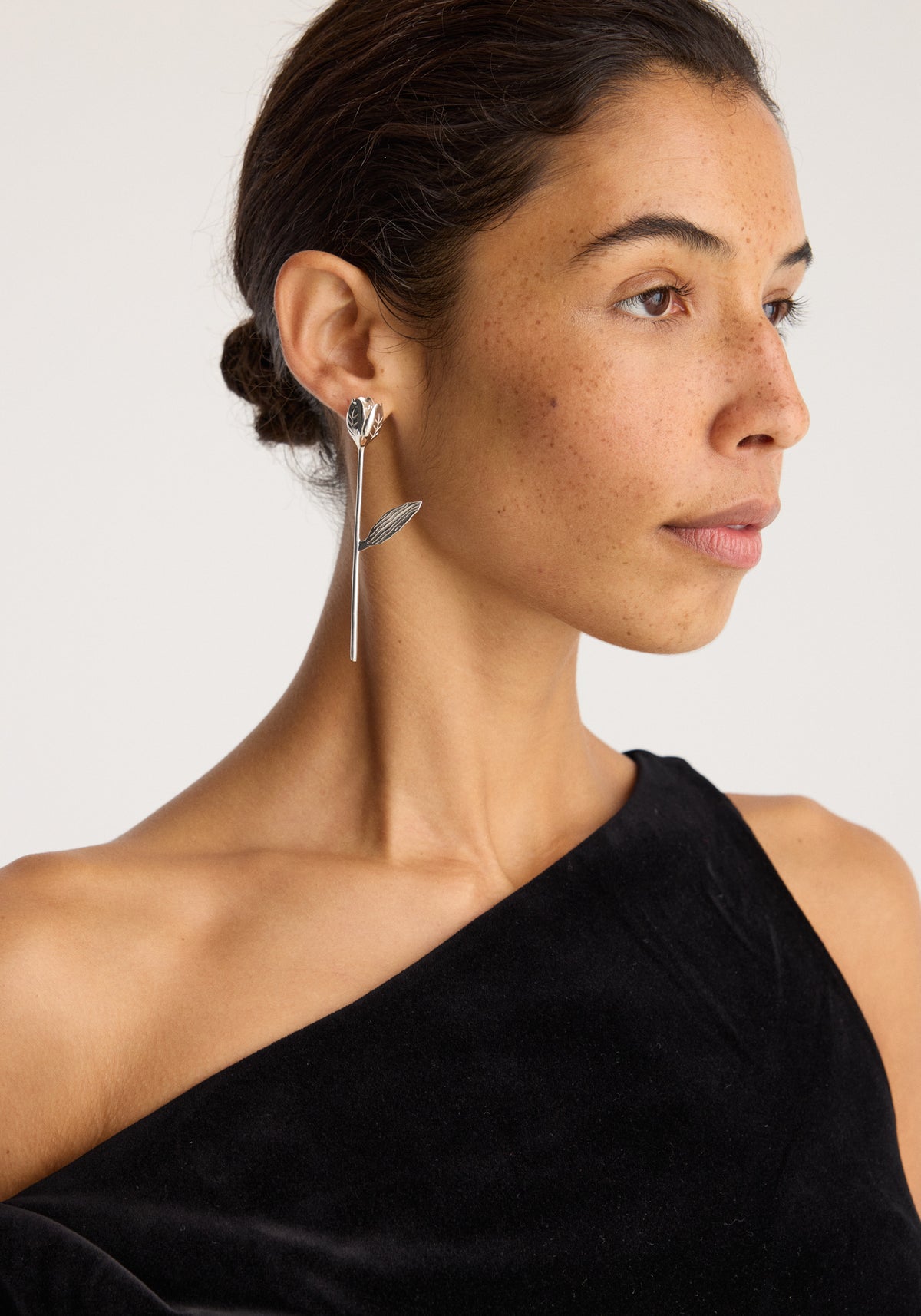 Tulip silver earring (single) | silver worn by a model featuring a delicate tulip flower and slender drop design in polished silver