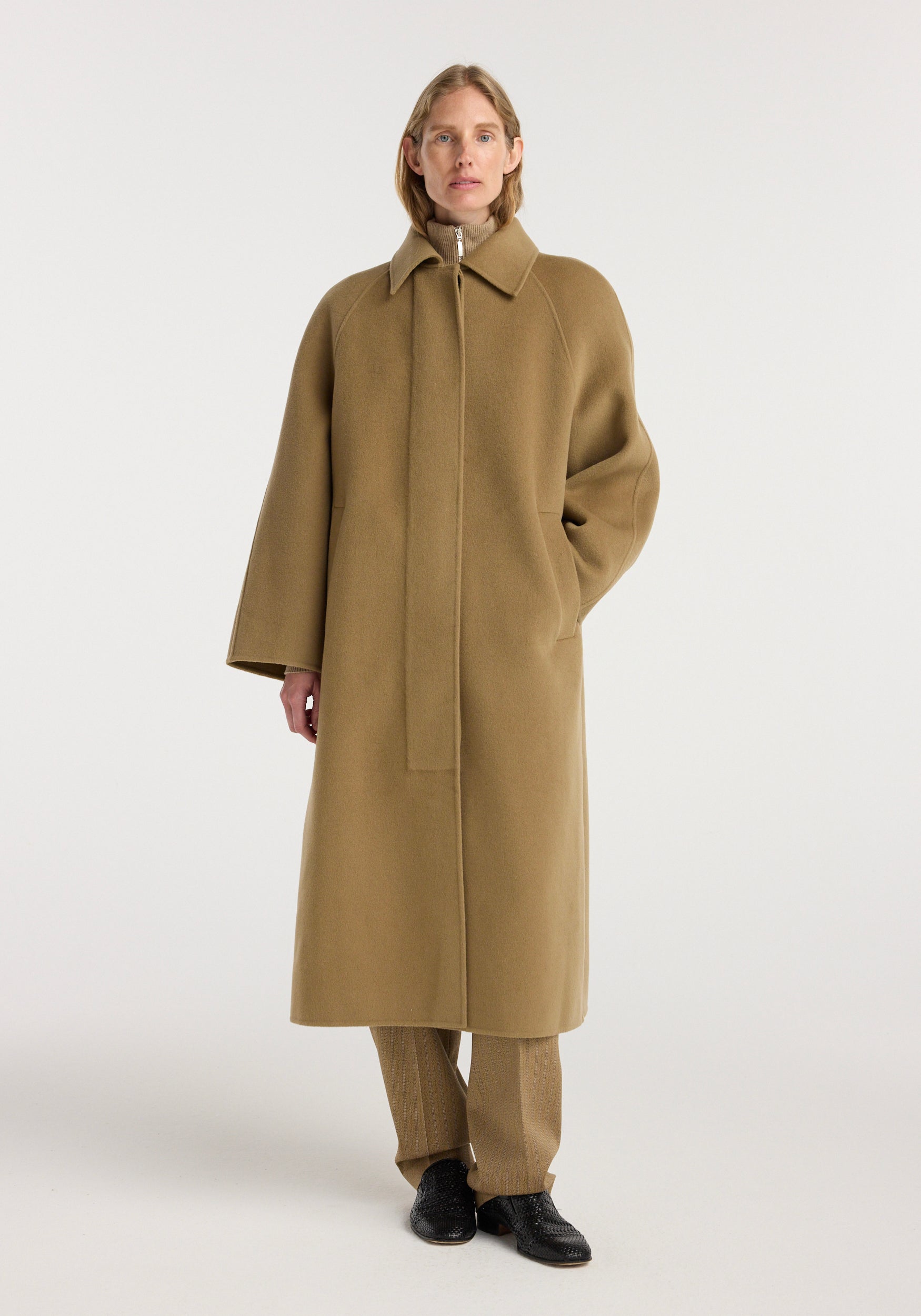 A woman wearing a long camel-colored Double-faced wool padded coat | camel with a concealed front closure and relaxed fit, styled with matching trousers and black shoes.