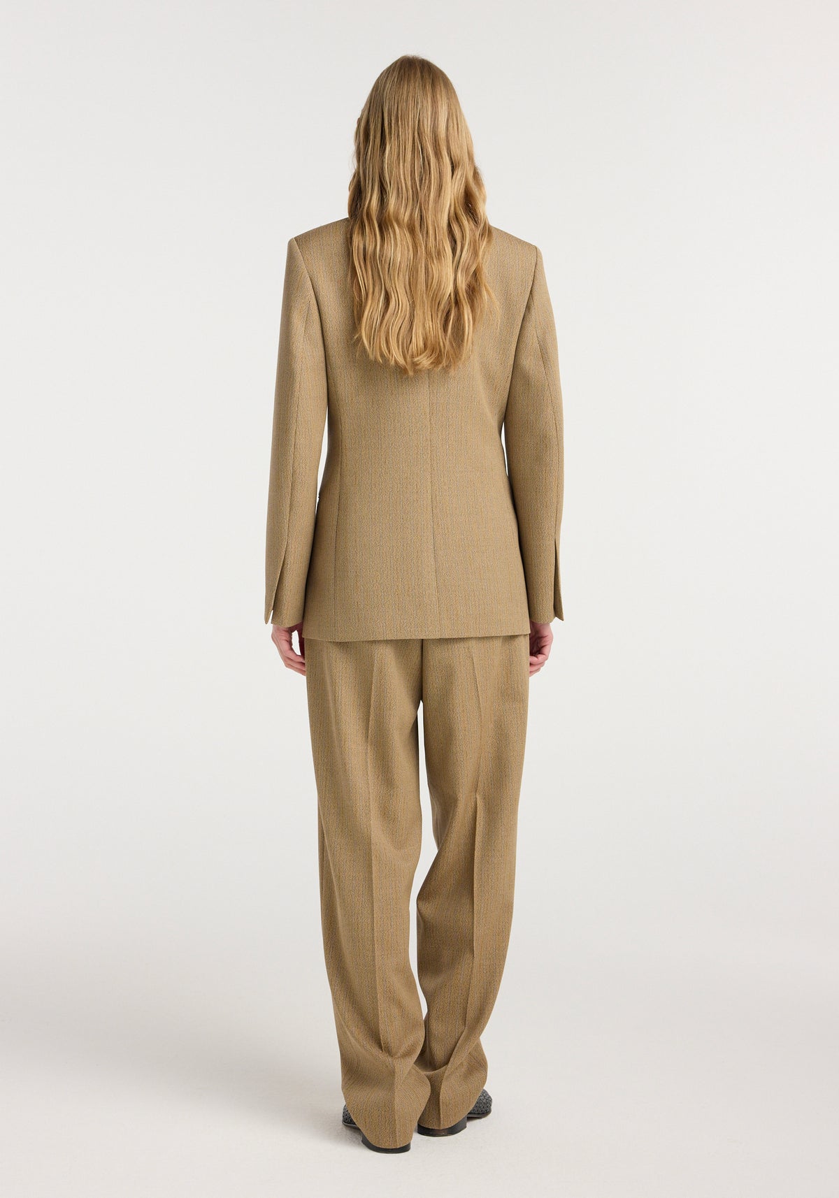 Back view of a person wearing an Overlap lapel blazer | heritage stripe in a beige and brown striped fabric, paired with matching wide-leg trousers against a plain background.