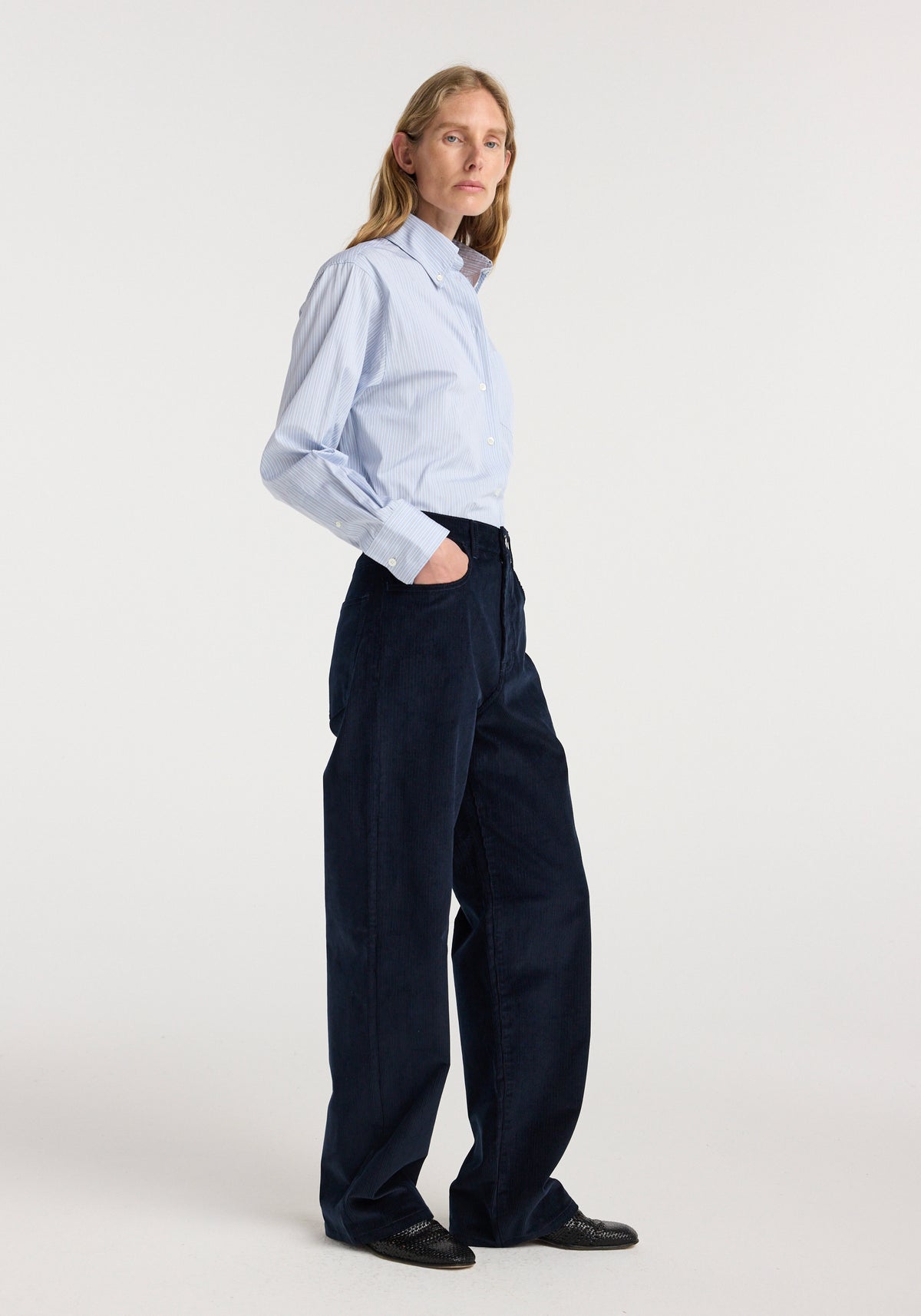 Model wearing Bruun - Signature baggy corduroy | night in dark navy corduroy, styled with a light blue button down shirt and black shoes in a studio setting