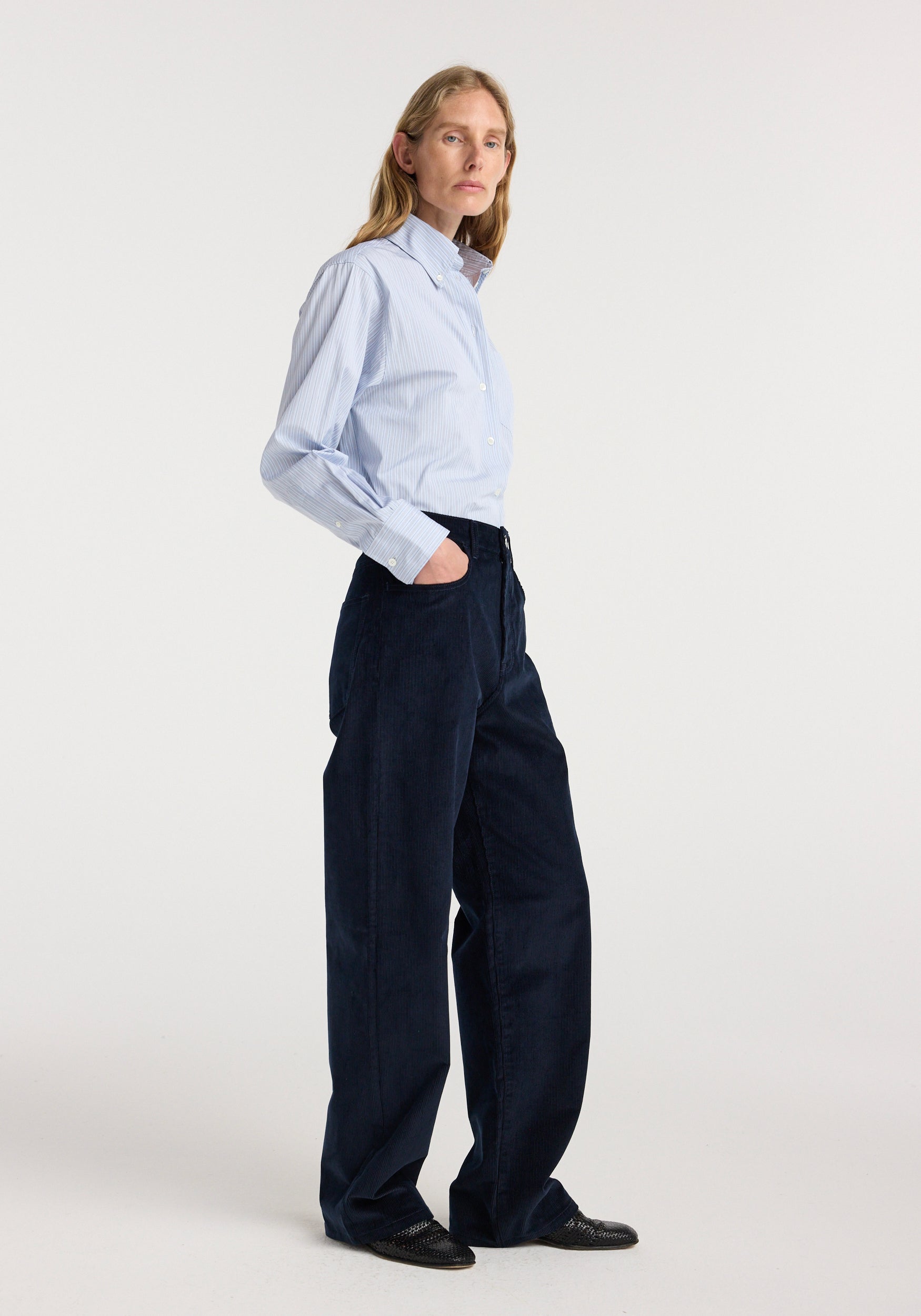 Model wearing Bruun - Signature baggy corduroy | night in dark navy corduroy, styled with a light blue button down shirt and black shoes in a studio setting