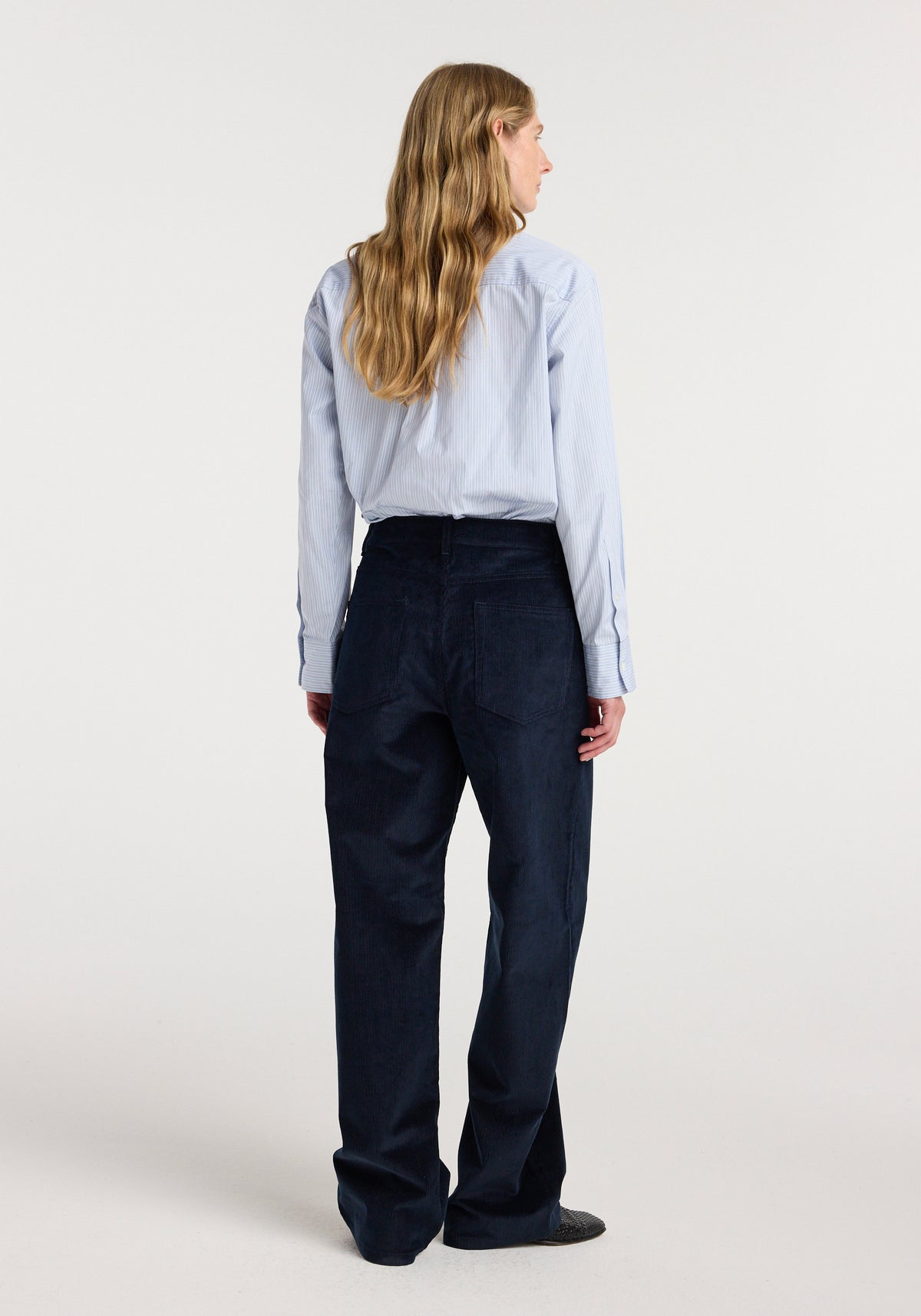 Back view of a model wearing Bruun - Signature baggy corduroy | night trousers with a relaxed fit and wide legs in dark navy corduroy.