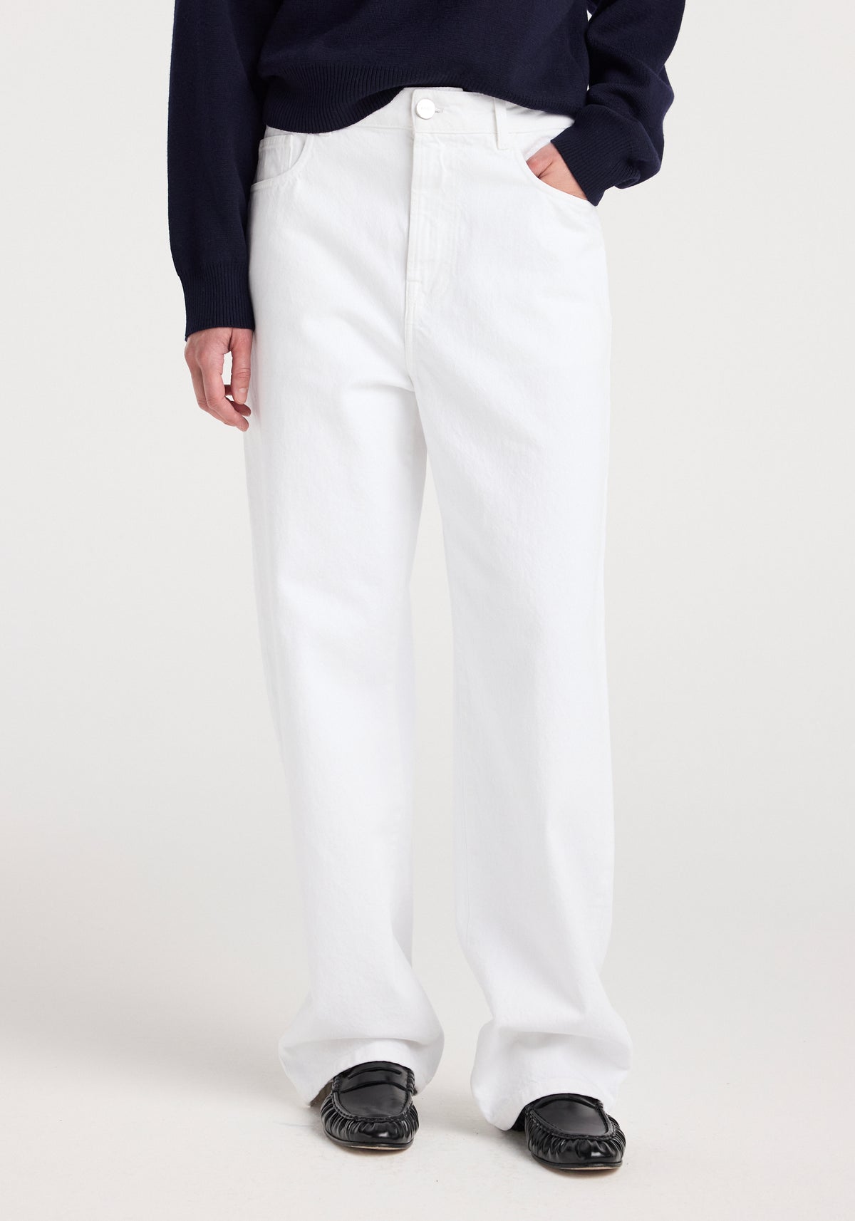 Model wearing Bruun - Signature baggy denim | optic white jeans with a relaxed fit, paired with a dark long-sleeve top and black shoes against a plain white background.