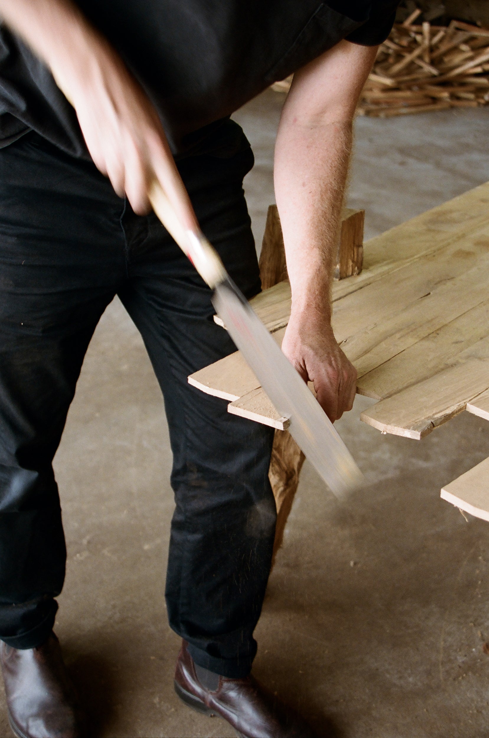 Person cutting a wooden table with a saw indoors.
