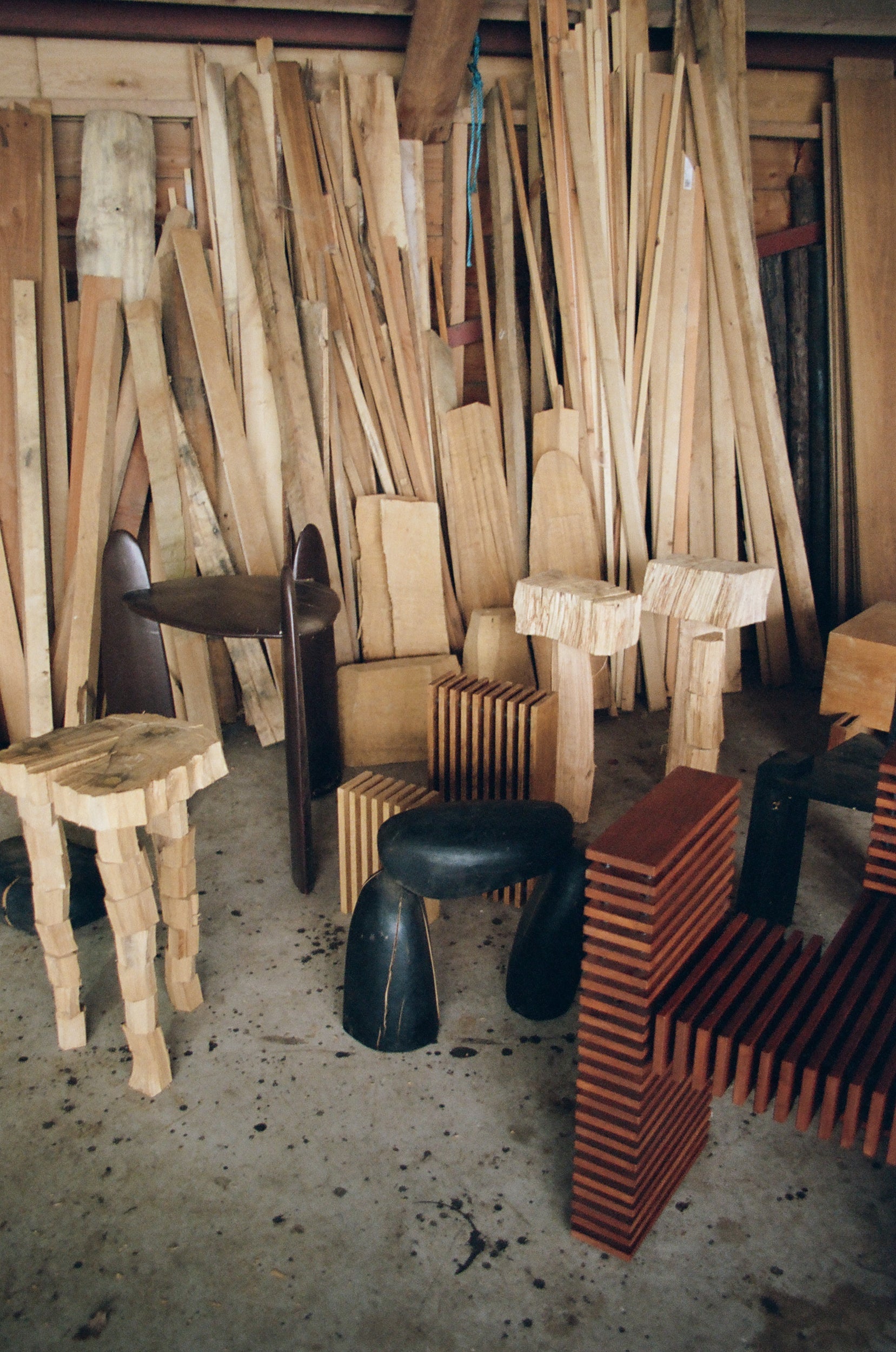 Different shaped stools and chairs in a work place with wooden panels standing against a wall in the background