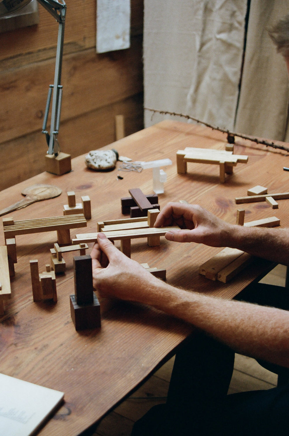 Man holding miniature models of wooden furniture on a wooden table 