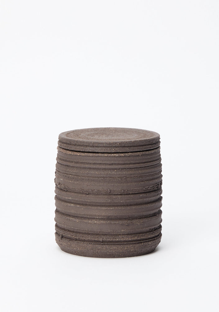 Diplomatico Scented Candle | soil: A cylinder of stacked, rough-edged discs, housed in a handmade ceramic vessel, reflecting a brutalist aesthetic with versatile post-use functionality.