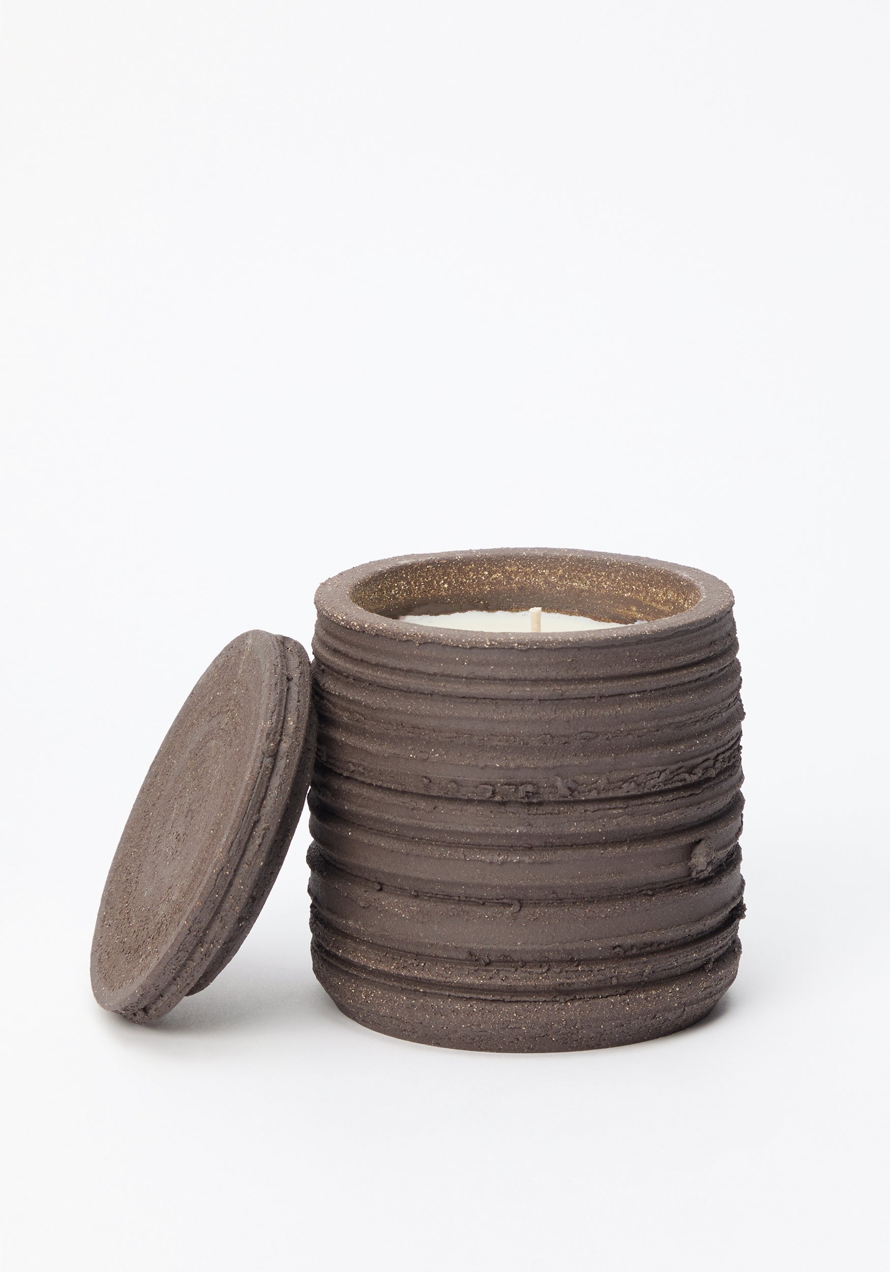 Opened dark brown textured ceramic jar candle with horizontal ridges and matching lid resting beside it, labeled Diplomatico Scented Candle | soil.