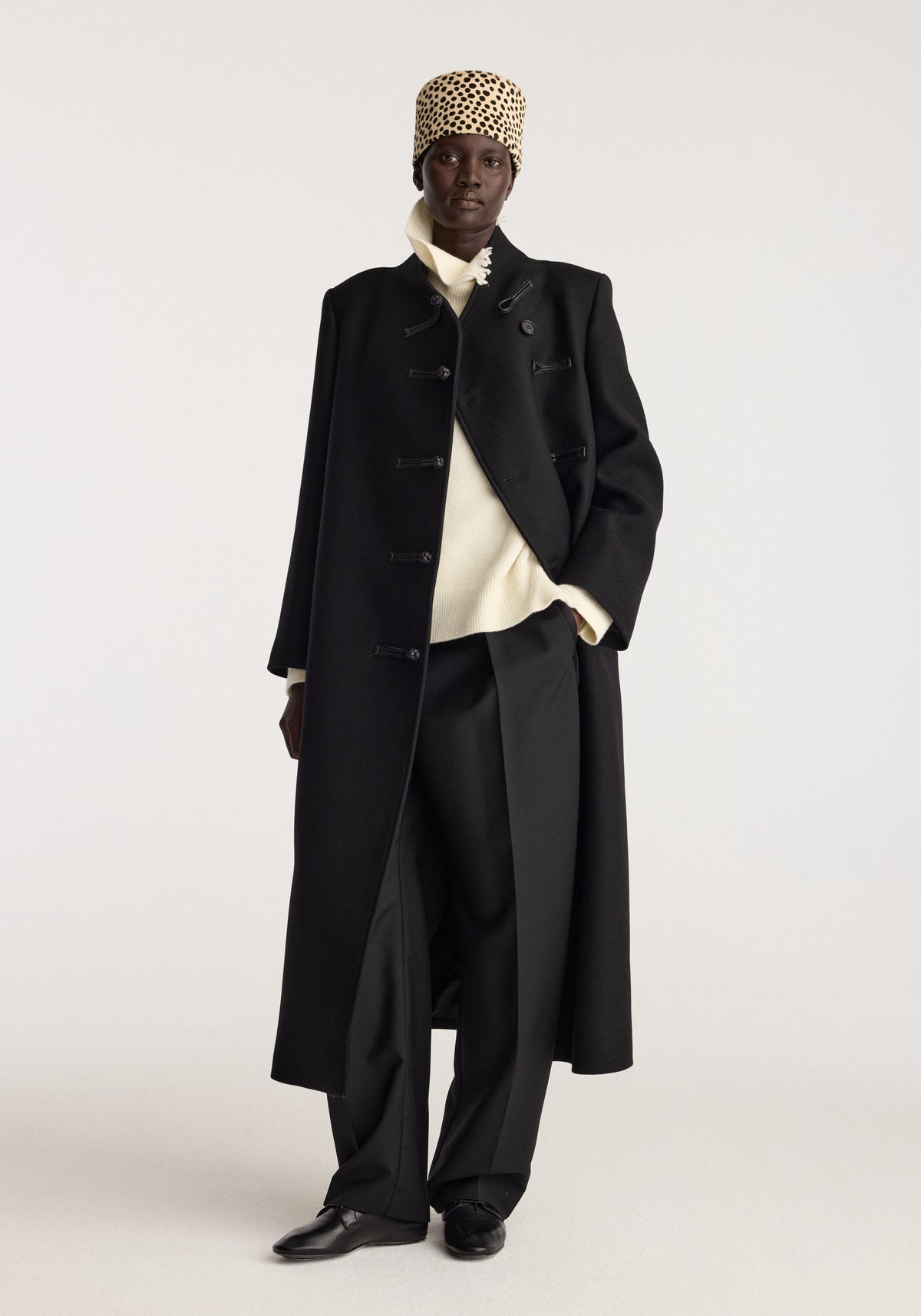 Cheetah leather hat | cheetah worn by a model in a black tailored coat with a cream sweater wide trousers and black shoes