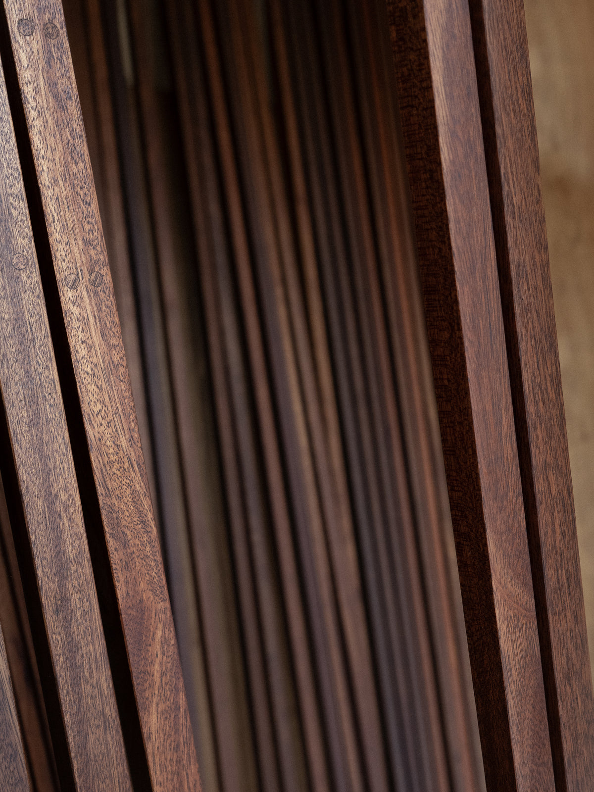 Close up view of dark brown wooden panels with narrow vertical grooves and varied natural grain textures creating a richly layered surface