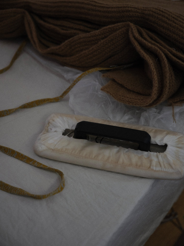 Vintage iron on a white surface with camel colored knitted fabric in the background