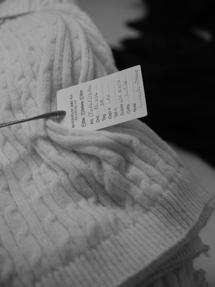 Close-up of a cable-knit sweater with a label on a blurred background