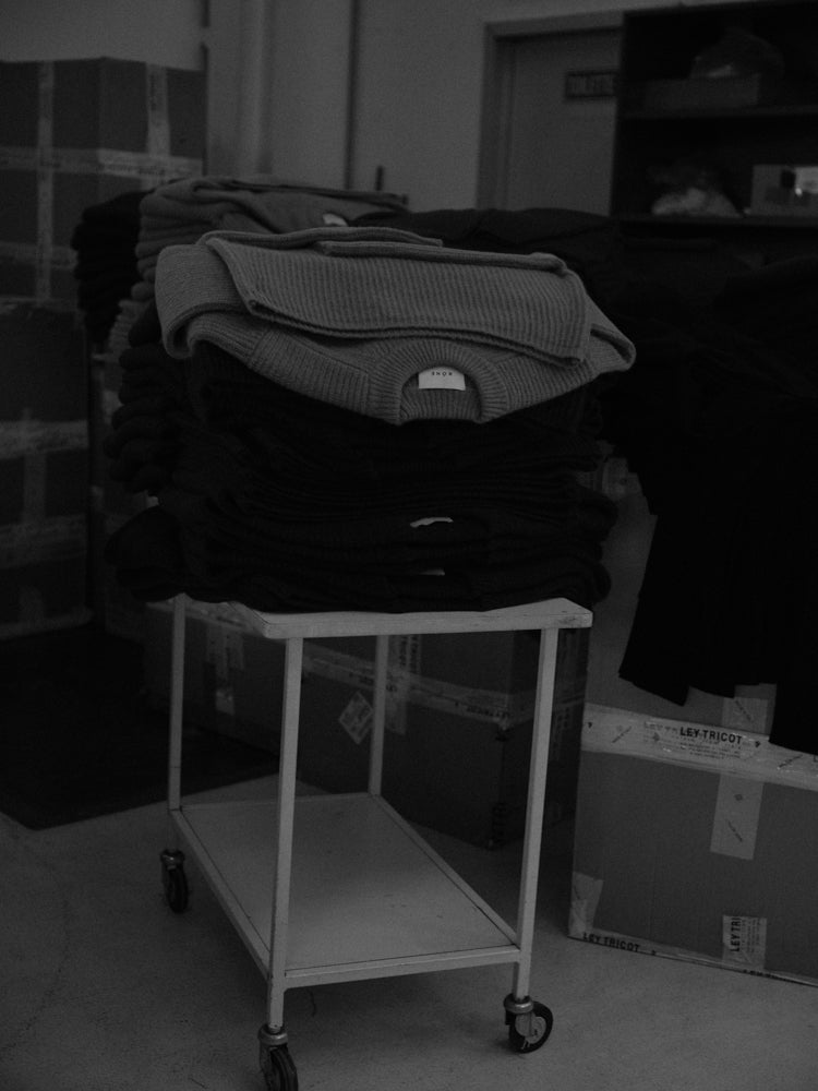 Stack of knitted sweaters on a rolling cart in a warehouse setting