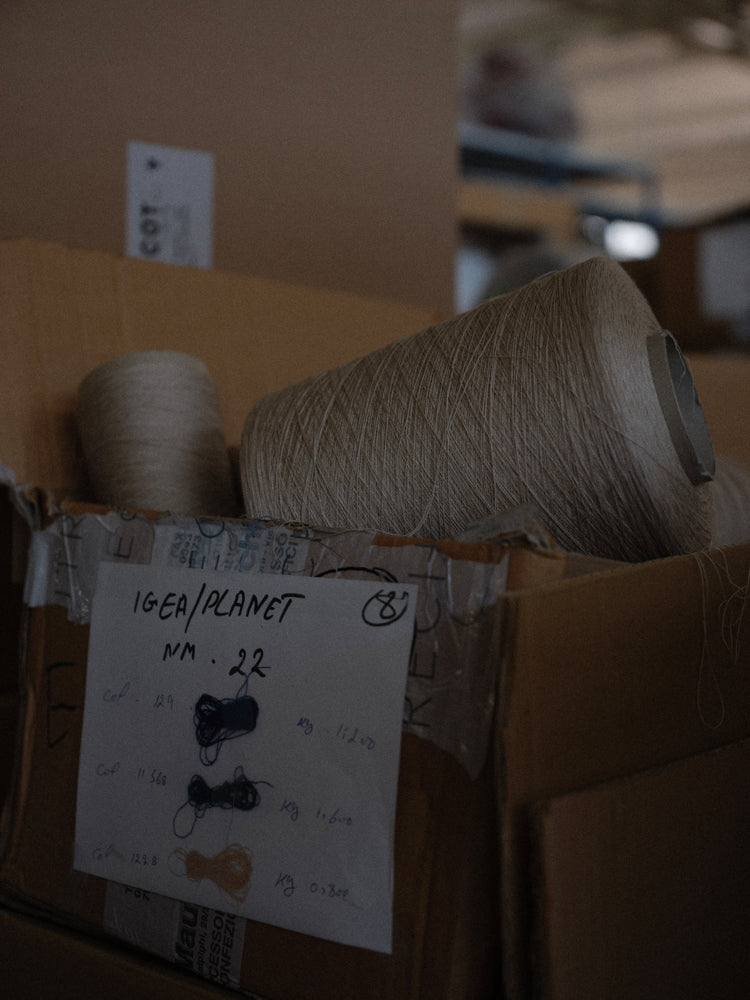 Box with spools of thread and a label with yarn swatches in a warehouse setting