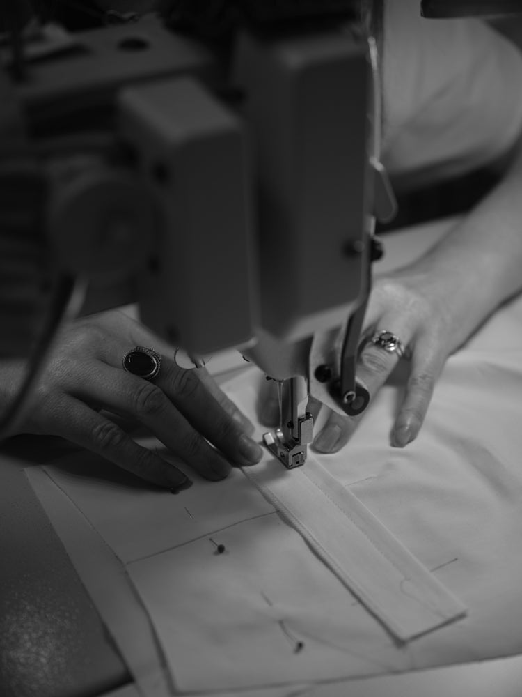 Person using a sewing machine with close-up focus on hands and machine.