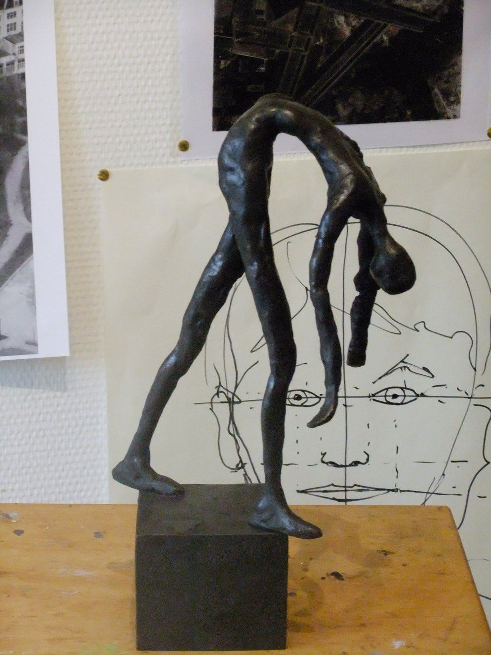 Bronze elegant figurine against a wall filled with art and sketches 