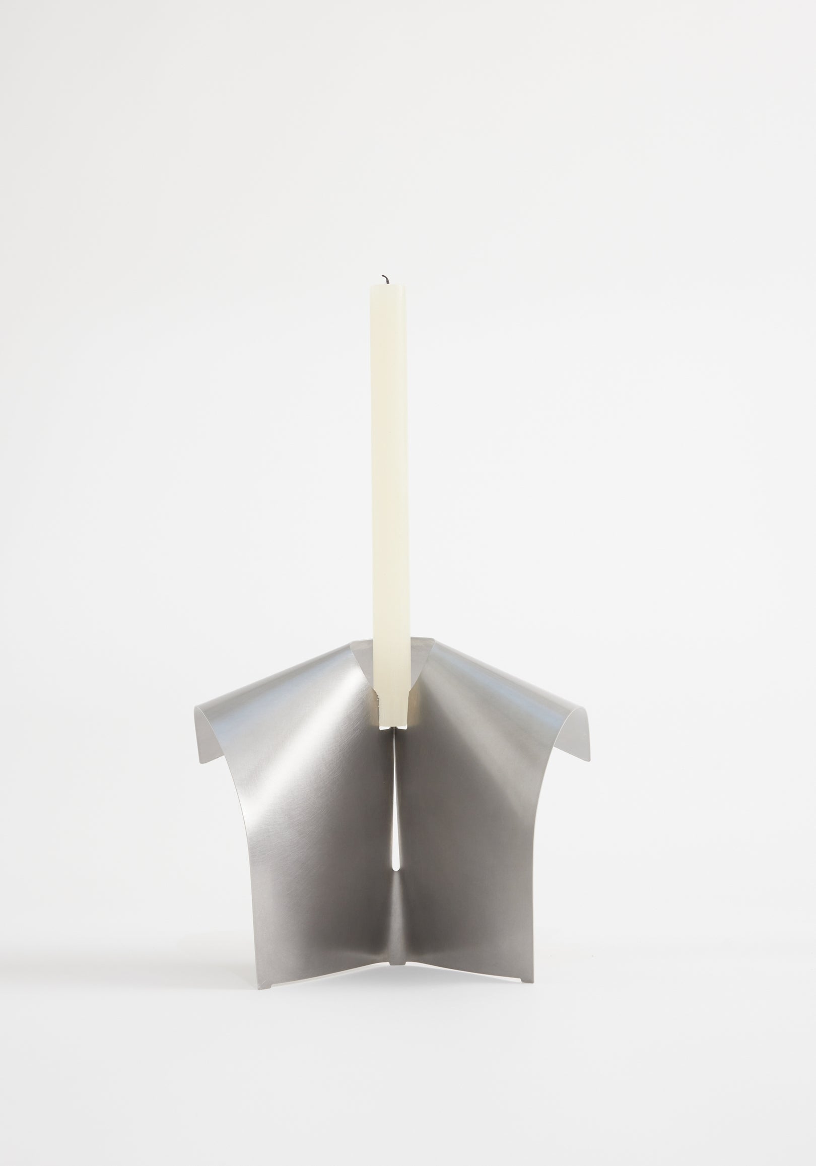 Minimalist stainless steel candle holder with a modern folded design holding a tall, slender white candle, Stainless steel candle holder | Stainless steel.