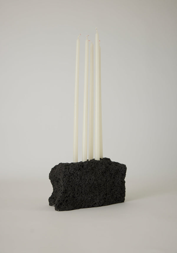 Sculptural Stone Candle Holder features six unlit white taper candles set in a handcrafted black porous lava stone block, measuring 10 cm high.