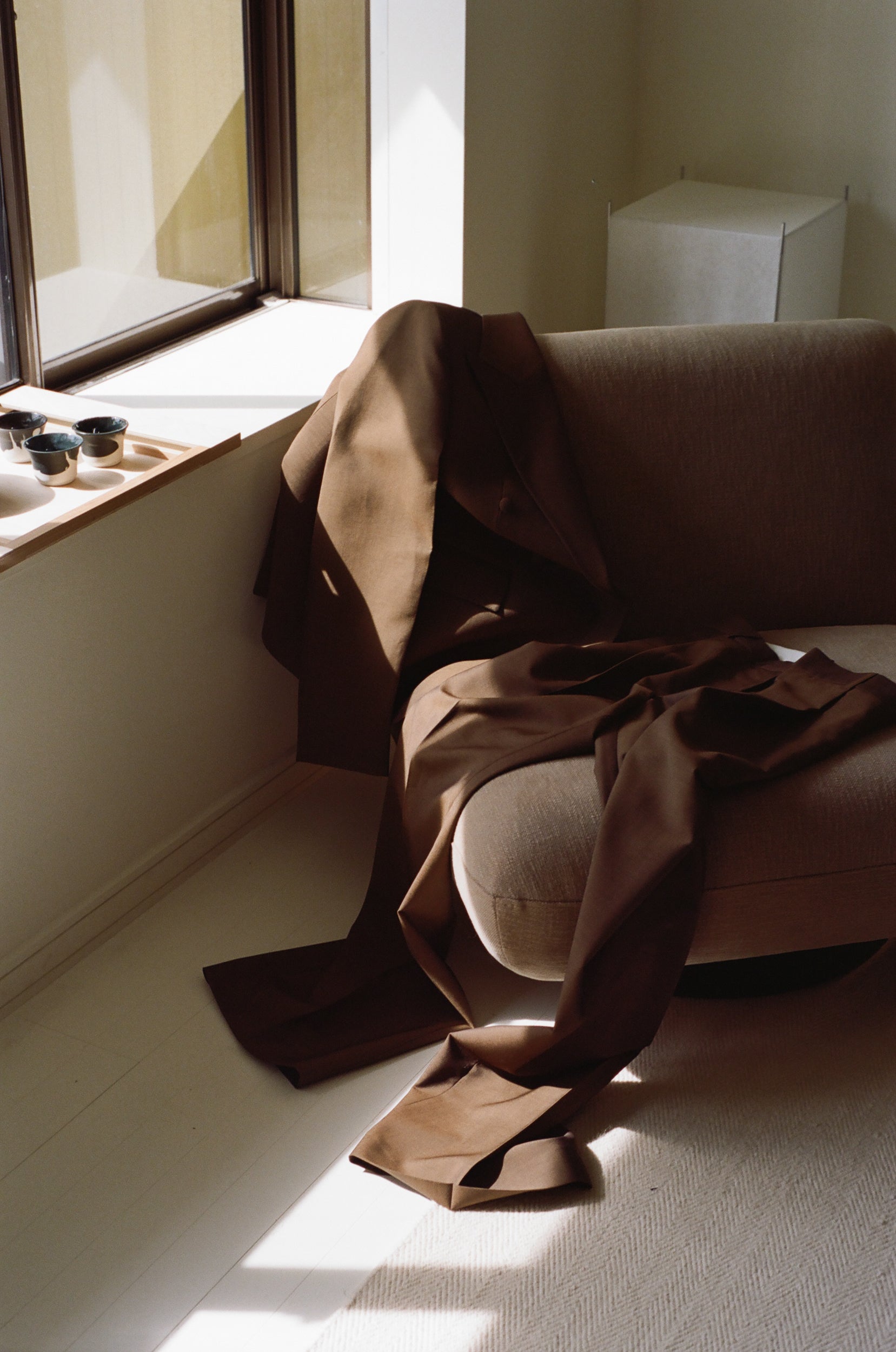 Suit jacket and trousers draped over a chair bathing in sunlight