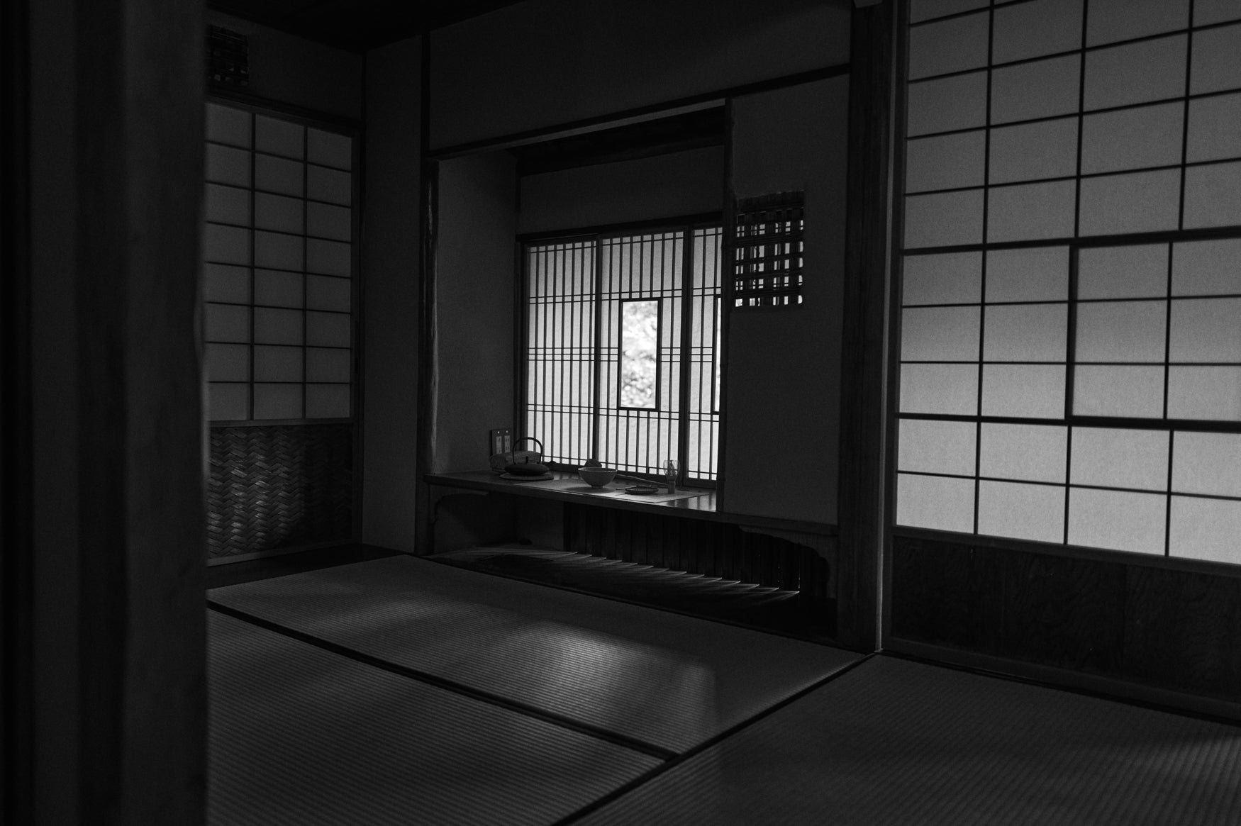 Black and white image of a room in a Japanese tea house with tatami mats and shoji windows. 