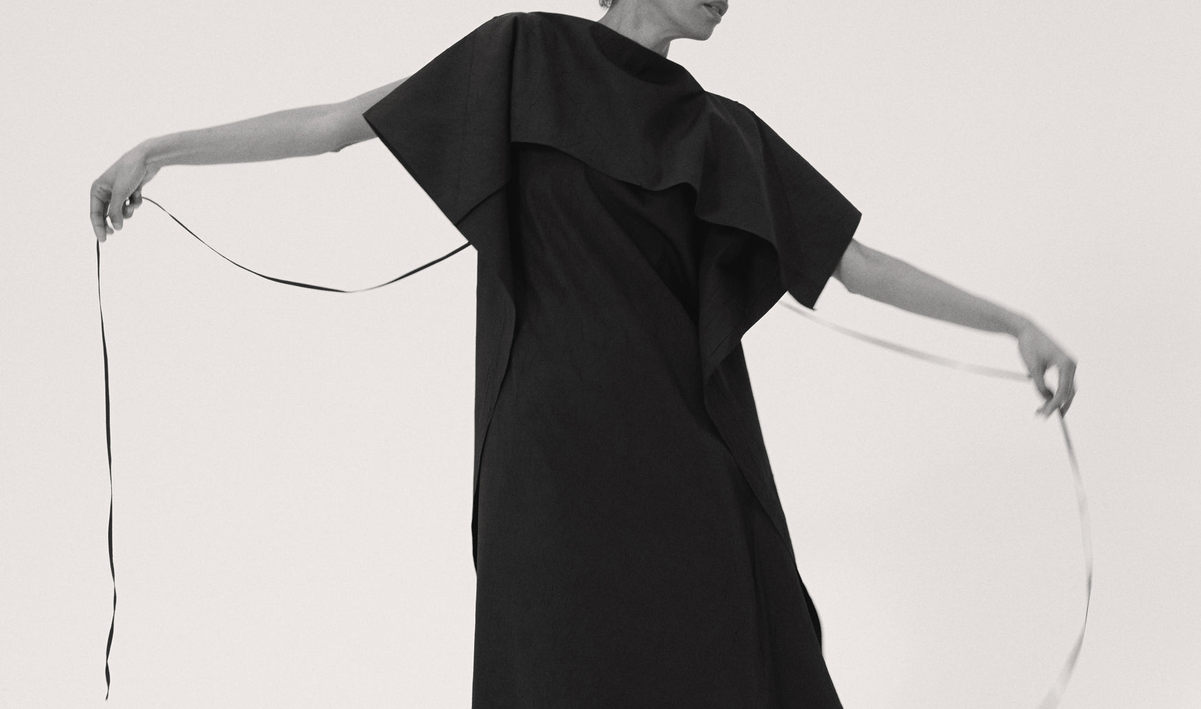 Black dress with ruffled details on a white background