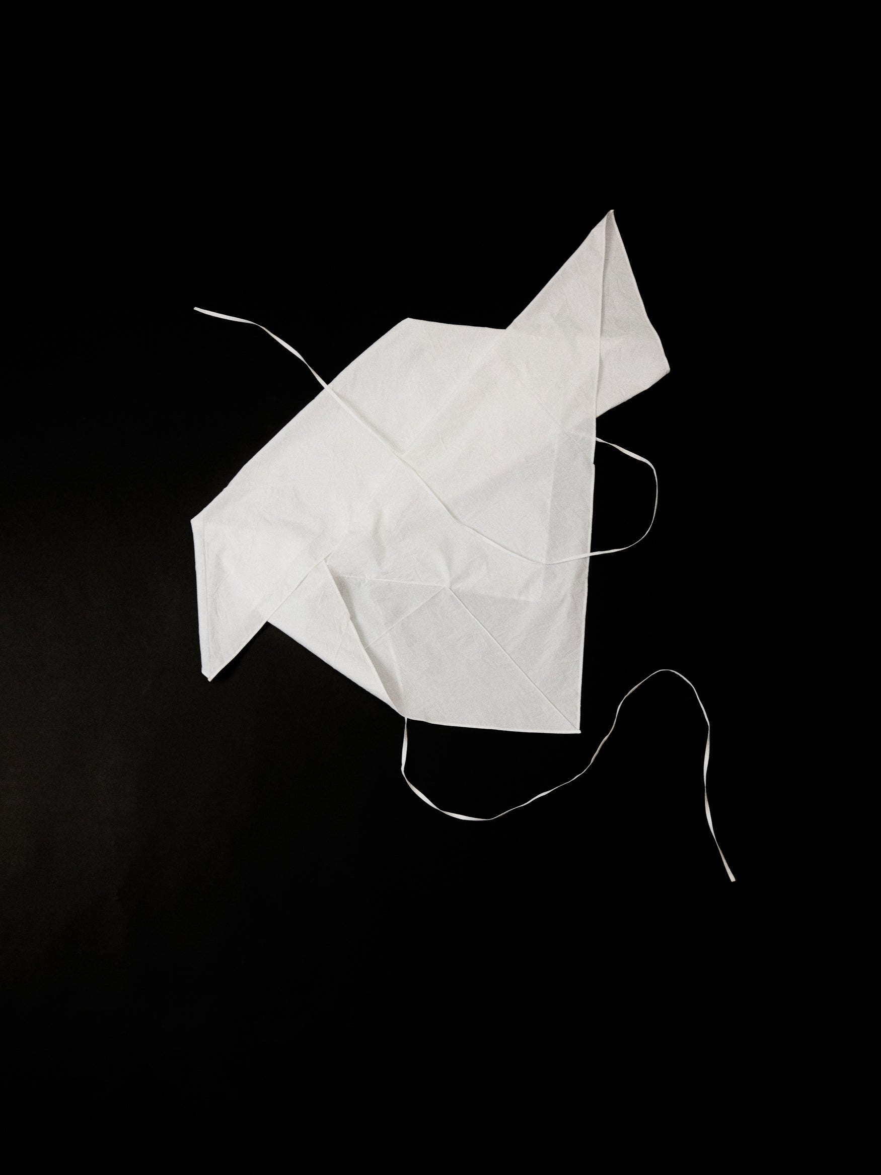 White cotton top in the shape of an origami crane on a black background