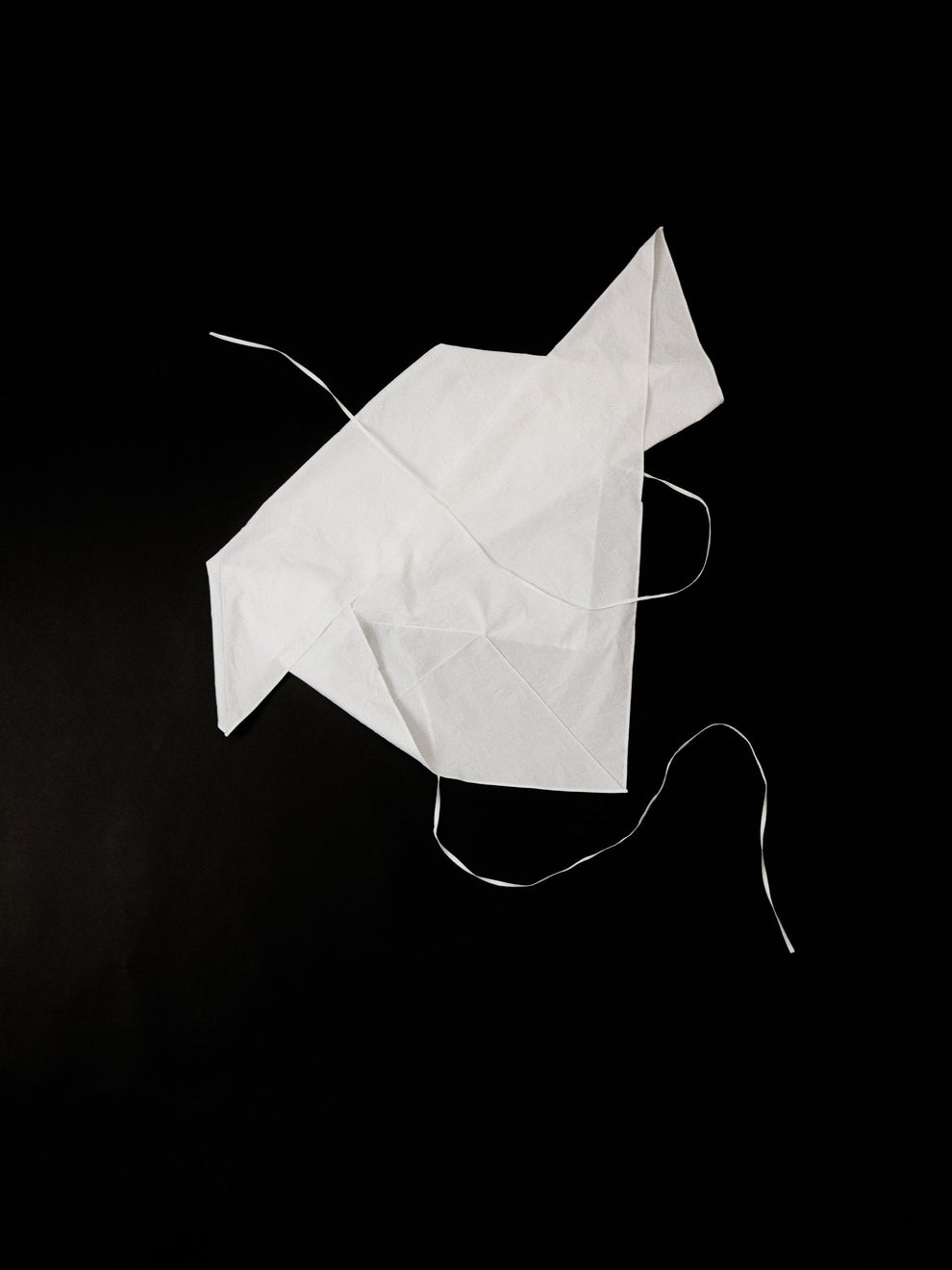 White cotton top in the shape of an origami crane on a black background