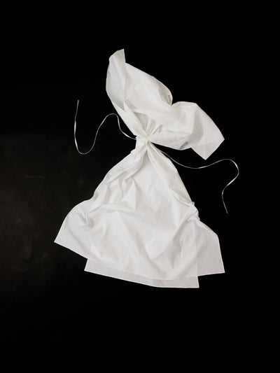 White cotton dress in a origami shape on a black background