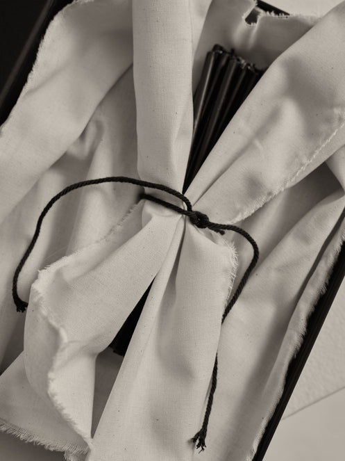 Candles 10mm | noir: A long black gift box with off-white cloth holds slender matte-black beeswax candles, tied with a dark cord, ideal for gifting.