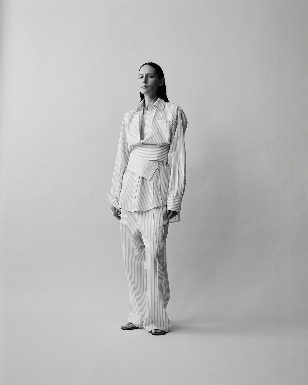 Person wearing a striped blouse with a striped belt wrapped around the waist and striped wide leg trousers