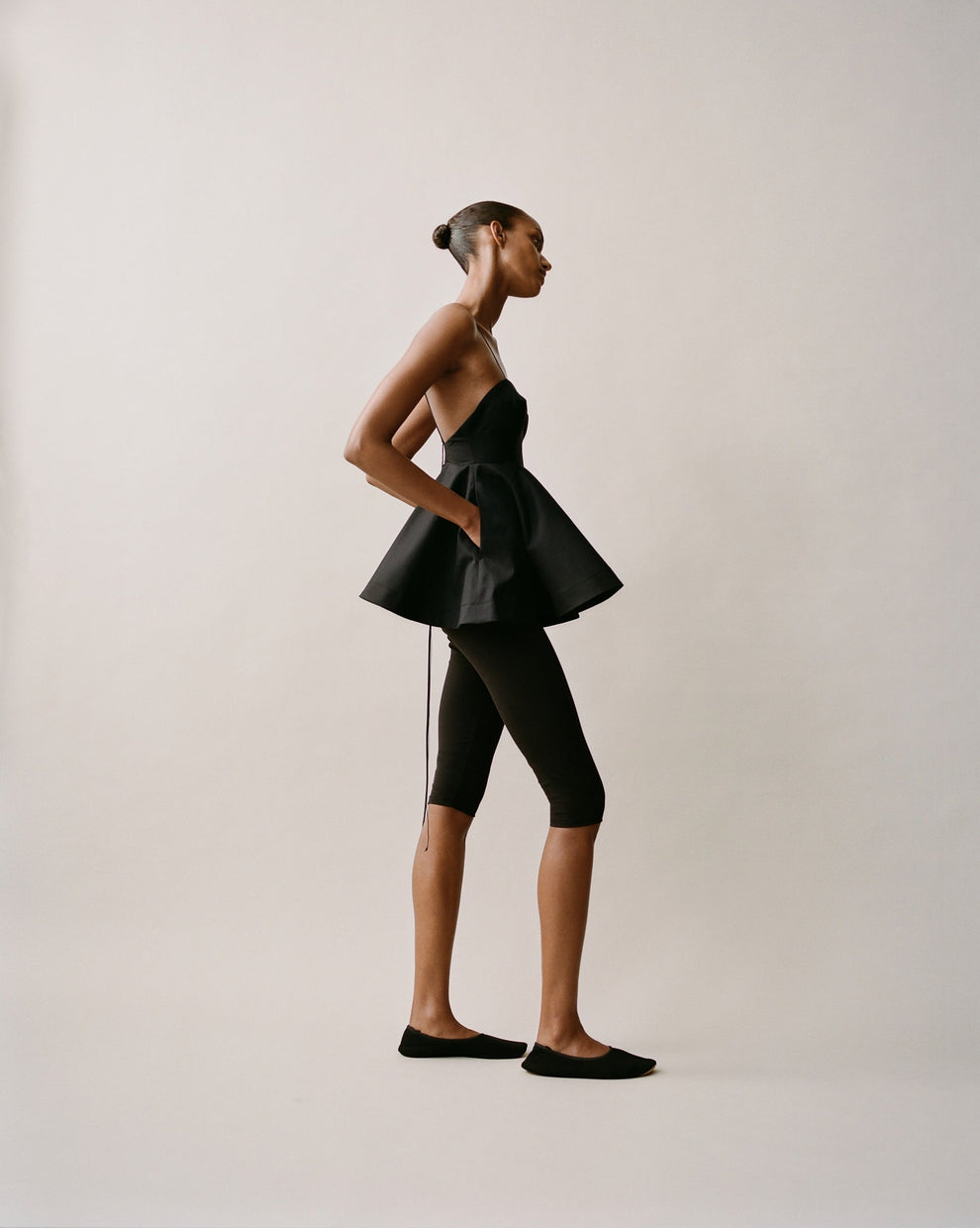 Woman wearing a black outfit with a peplum top on a plain background