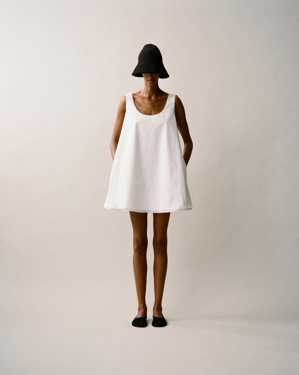 Person wearing a white short aline dress against a white backdrop 