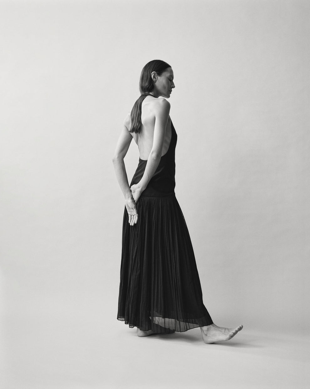 Person wearing a black halter dress against a white backdrop 