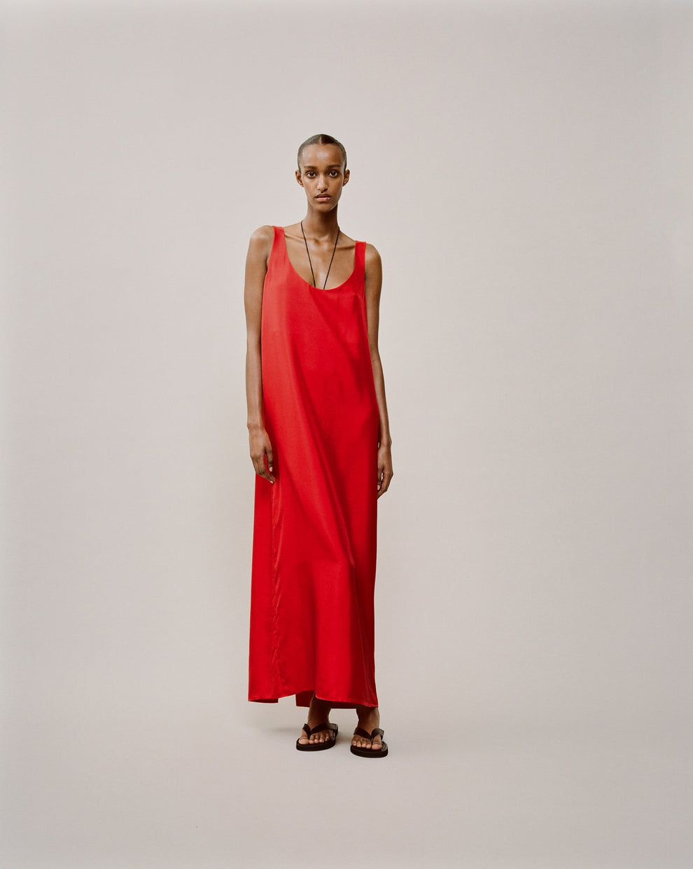 Person wearing a ankle length red silk scoop neck dress