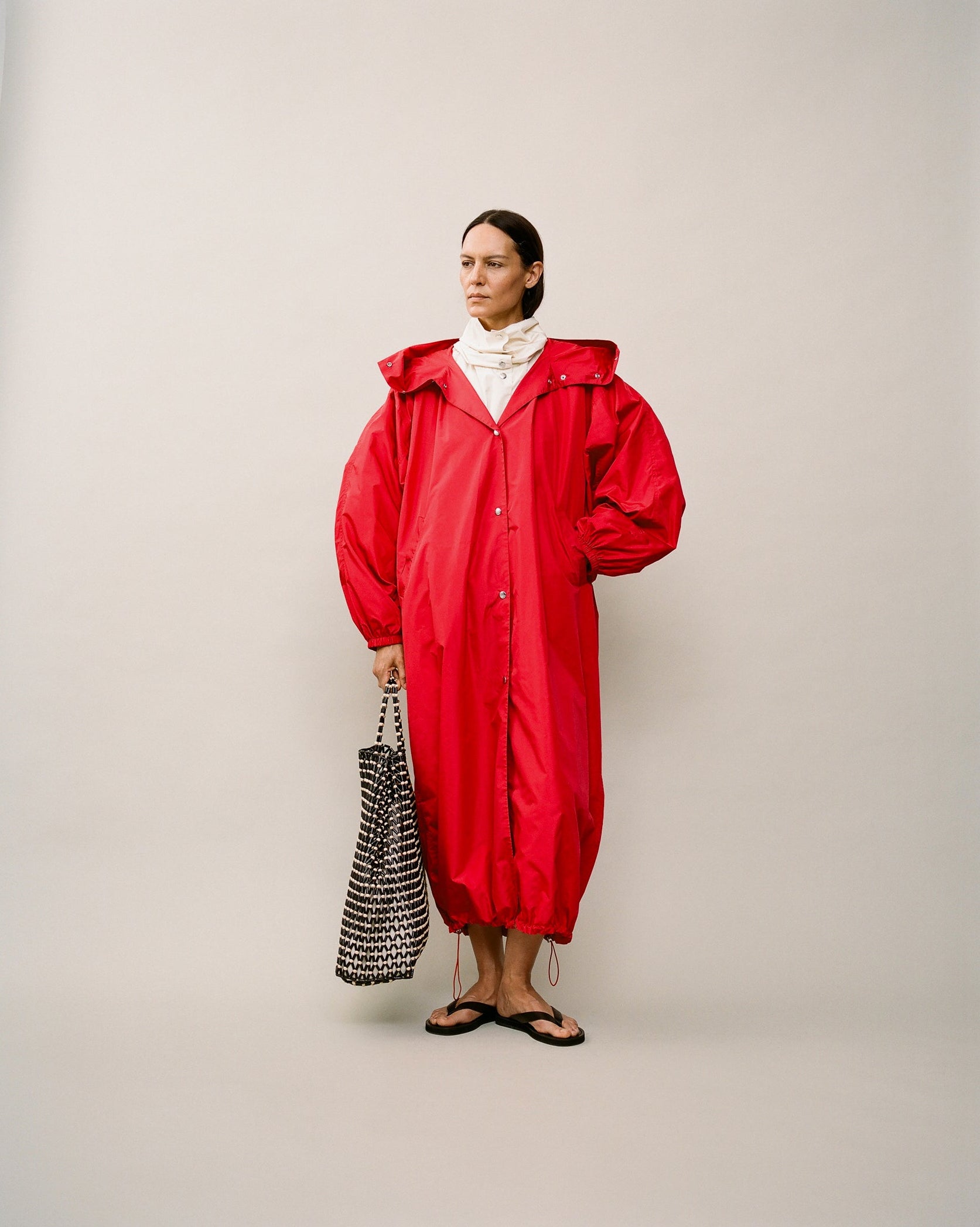 Woman wearing a long voluminous red coat. 