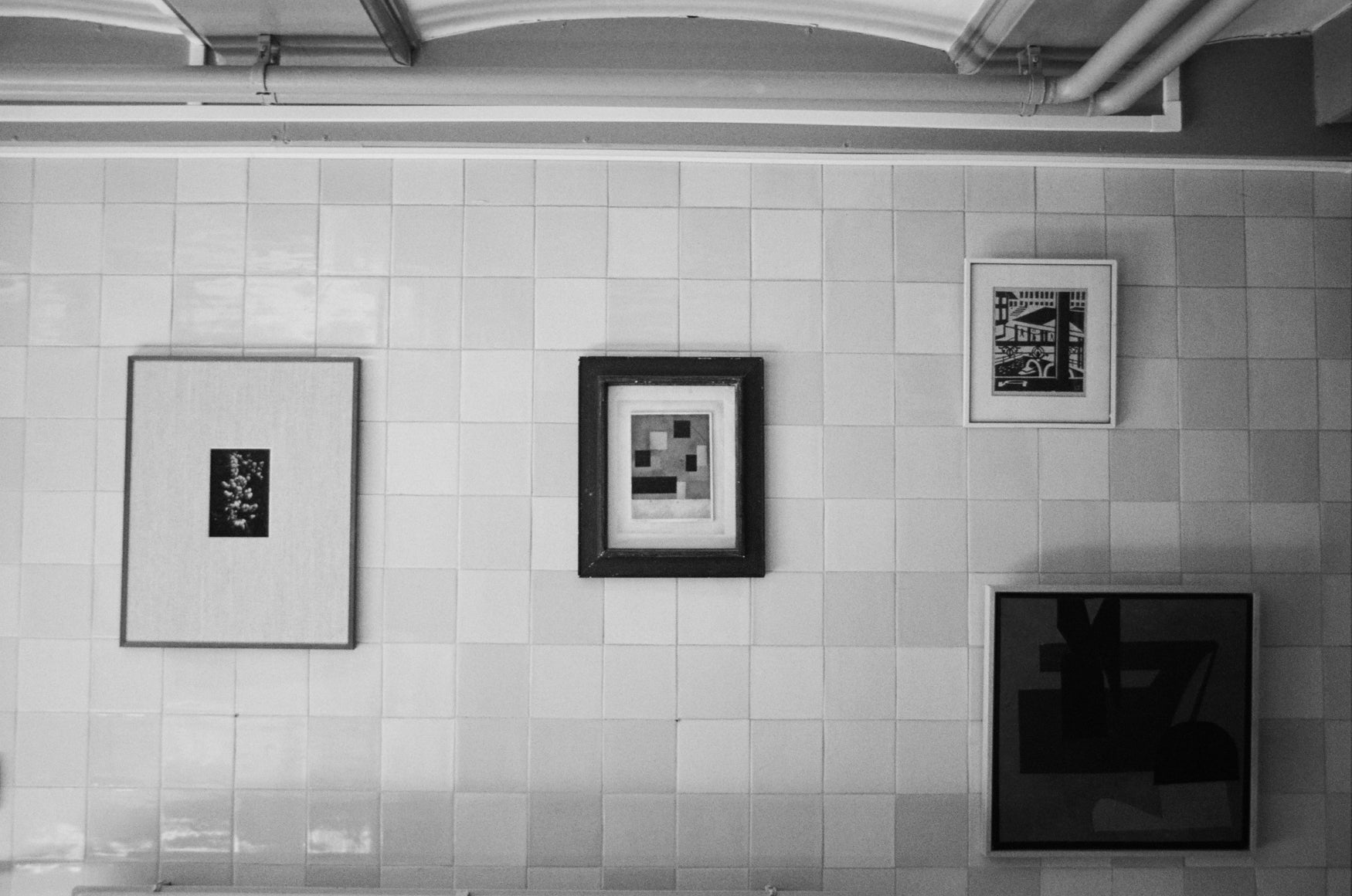 Four art pieces hung on a tiled wall