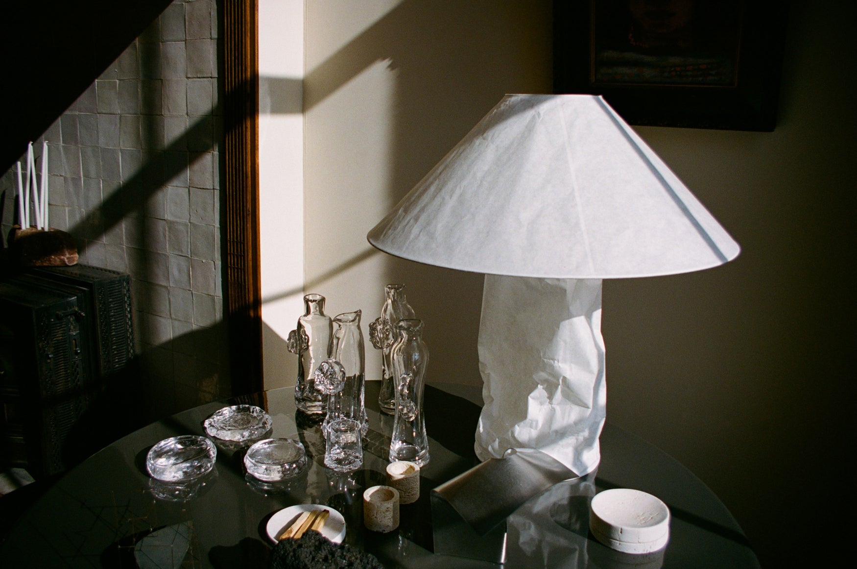 White lampshade on a dark table with decorative items and glass carafes around it