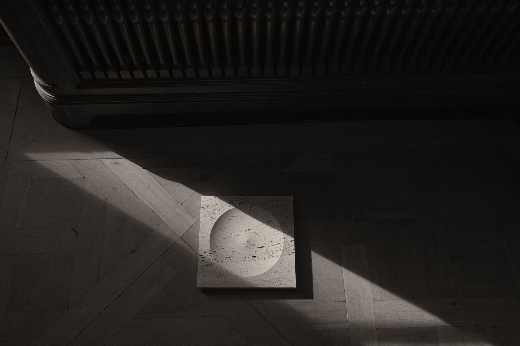 Travertin square tray layed on a wooden floor with a shadow play