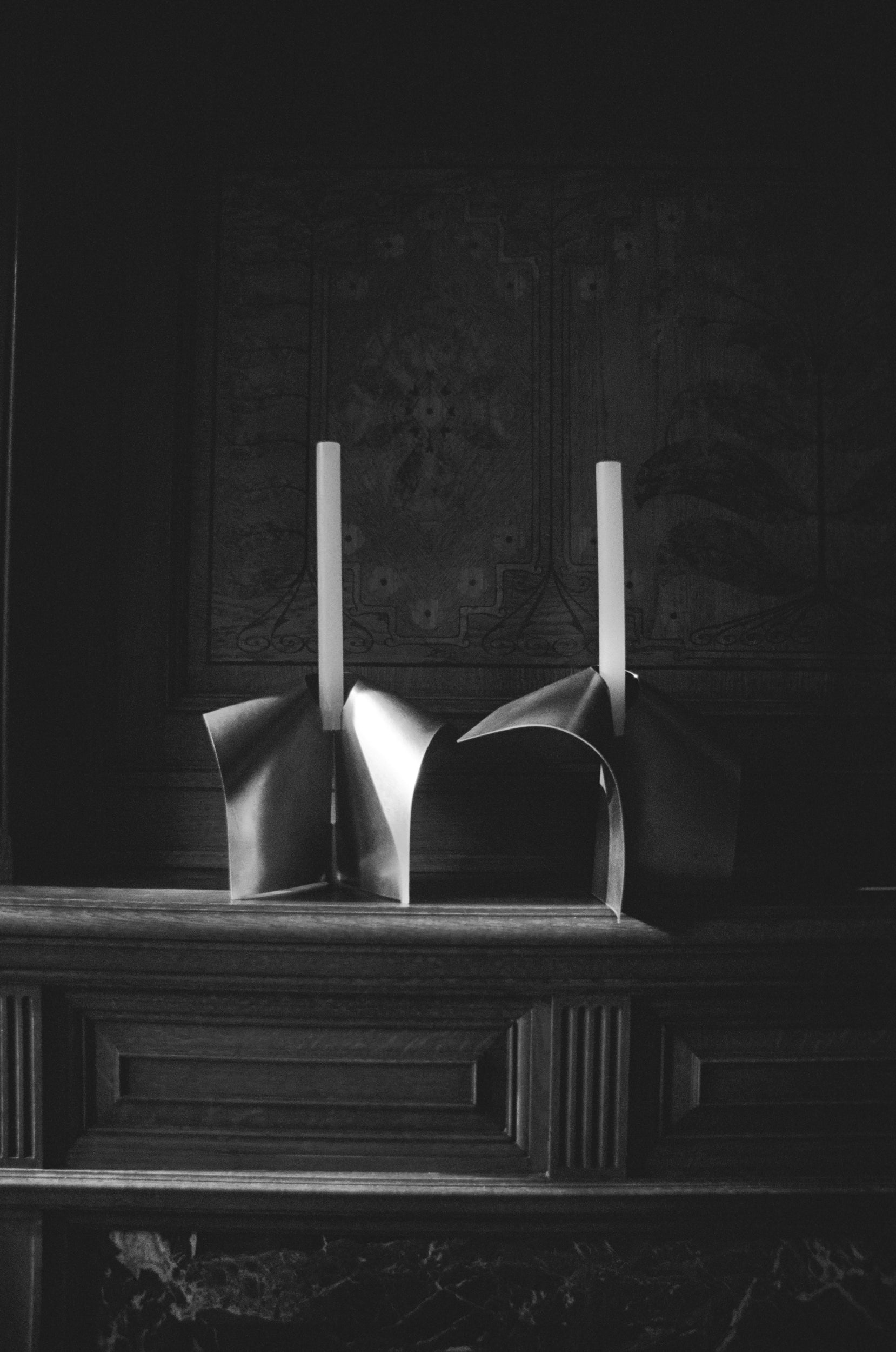 Two stainless steel candle holders on a wooden fire place