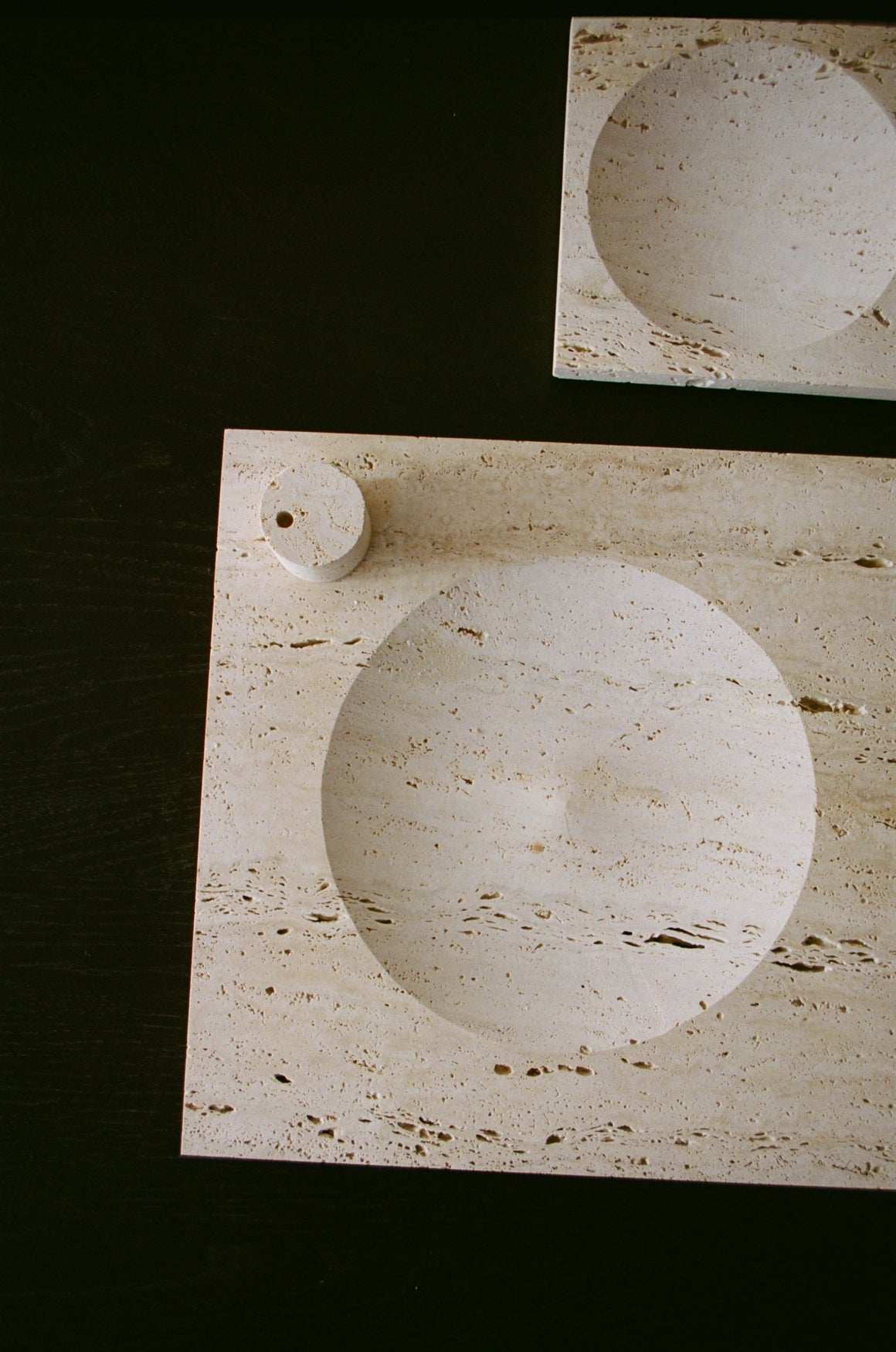 Two travertin square trays in different sizes on a dark background