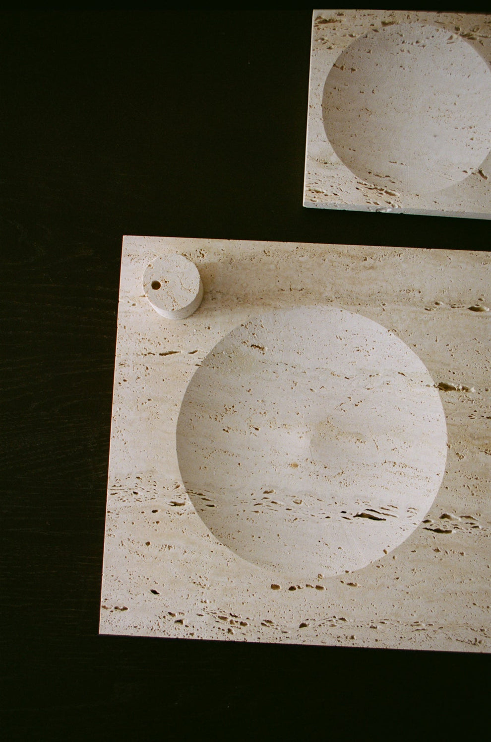 Two travertin square trays in different sizes on a dark background