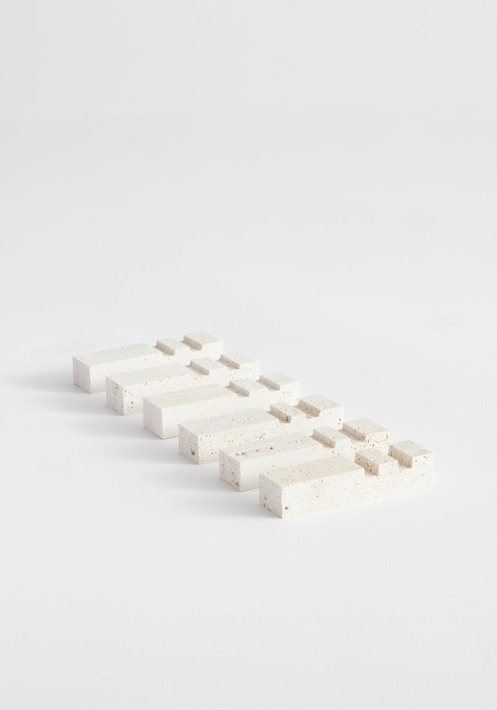 Chopstick holders | travertine: A series of speckled rectangular travertine blocks in stepped arrangements, handcrafted by Louis Crombag from Italian travertine, showcasing unique textures.