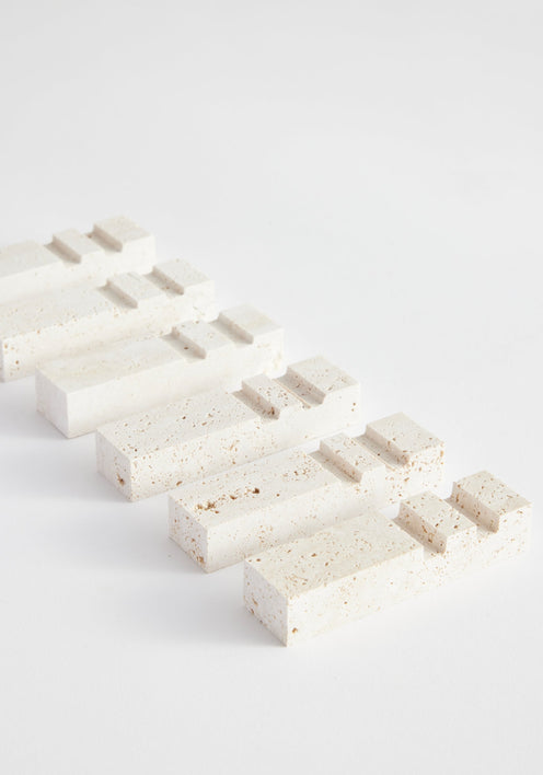 Travertine chopstick holders, handcrafted by Louis Crombag, showcasing a modular design with raised steps, made from leftover Italian travertine, arranged diagonally.