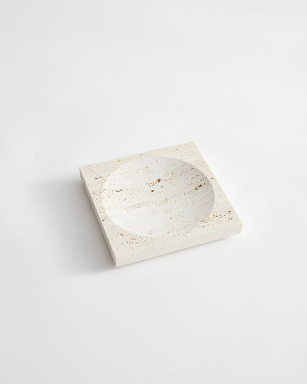Small tray | travertine: A handcrafted, pale-beige square stone tray with a round carved indent, made from Italian travertine by Dutch artist Louis Crombag.