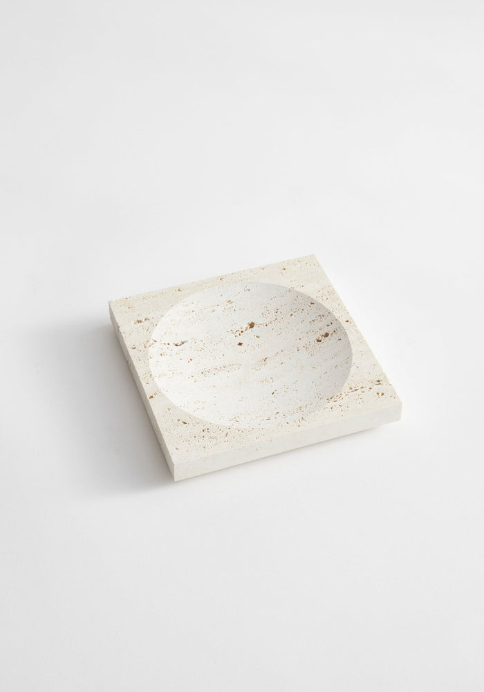 Small tray | travertine: A handcrafted, pale-beige square stone tray with a round carved indent, made from Italian travertine by Dutch artist Louis Crombag.