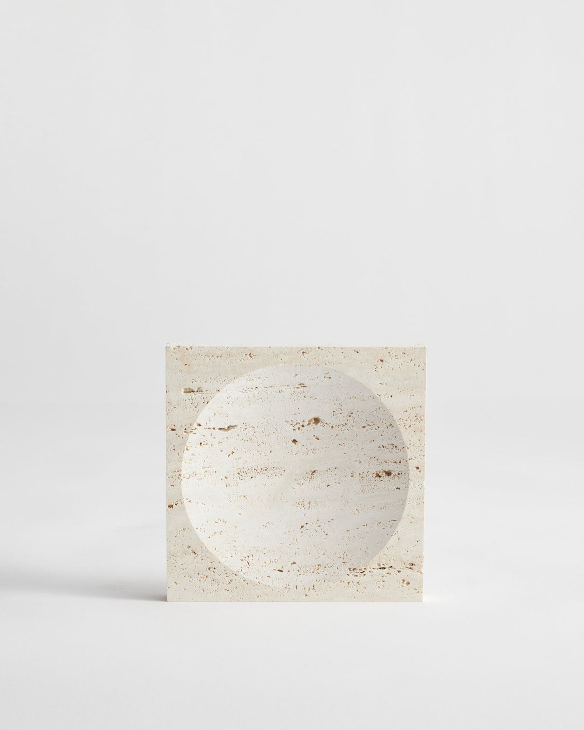 Small tray | travertine: A handcrafted square travertine block with a circular indent, showcasing minimalist design. Made in the Netherlands by artist Louis Crombag.
